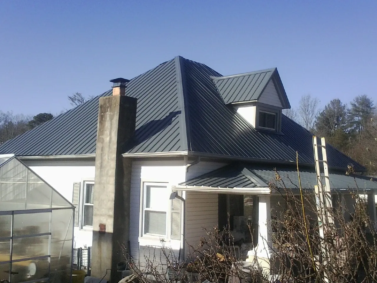 Dark blue standing seam metal roof on a white farmhouse with dormer — Slate & Tile Roof Repair by Roofing Brothers in Lawrenceburg