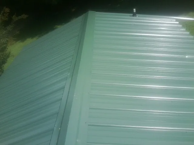 New green metal panels meeting at the ridge of a roof — Flat Roof Repair work by our crew in Lawrenceburg