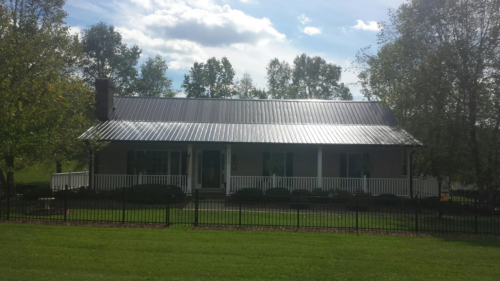 Gray metal roof on a brick ranch with a full width front porch — Gutter Guard Installation work by our crew in Lawrenceburg